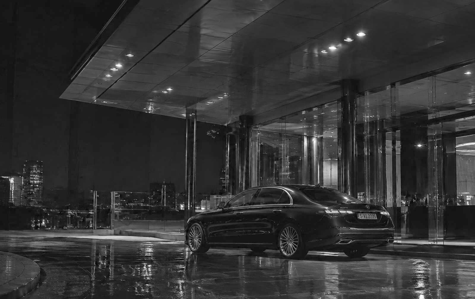 Executive vehicle waiting beneath a building canopy at night